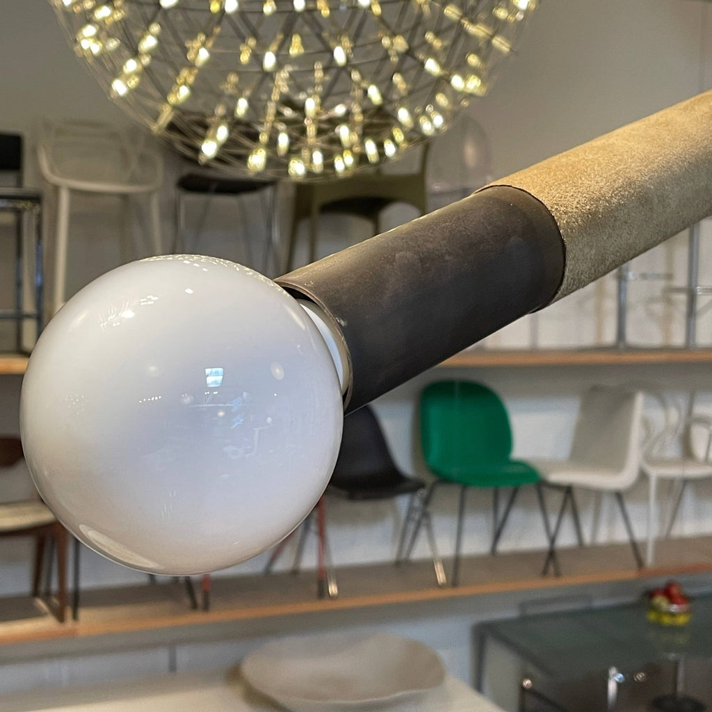 A large Apparatus Studio Suede Wrapped Arrow Ceiling Light featuring two metal rods and a glass globe, designed by Apparatus Studio.