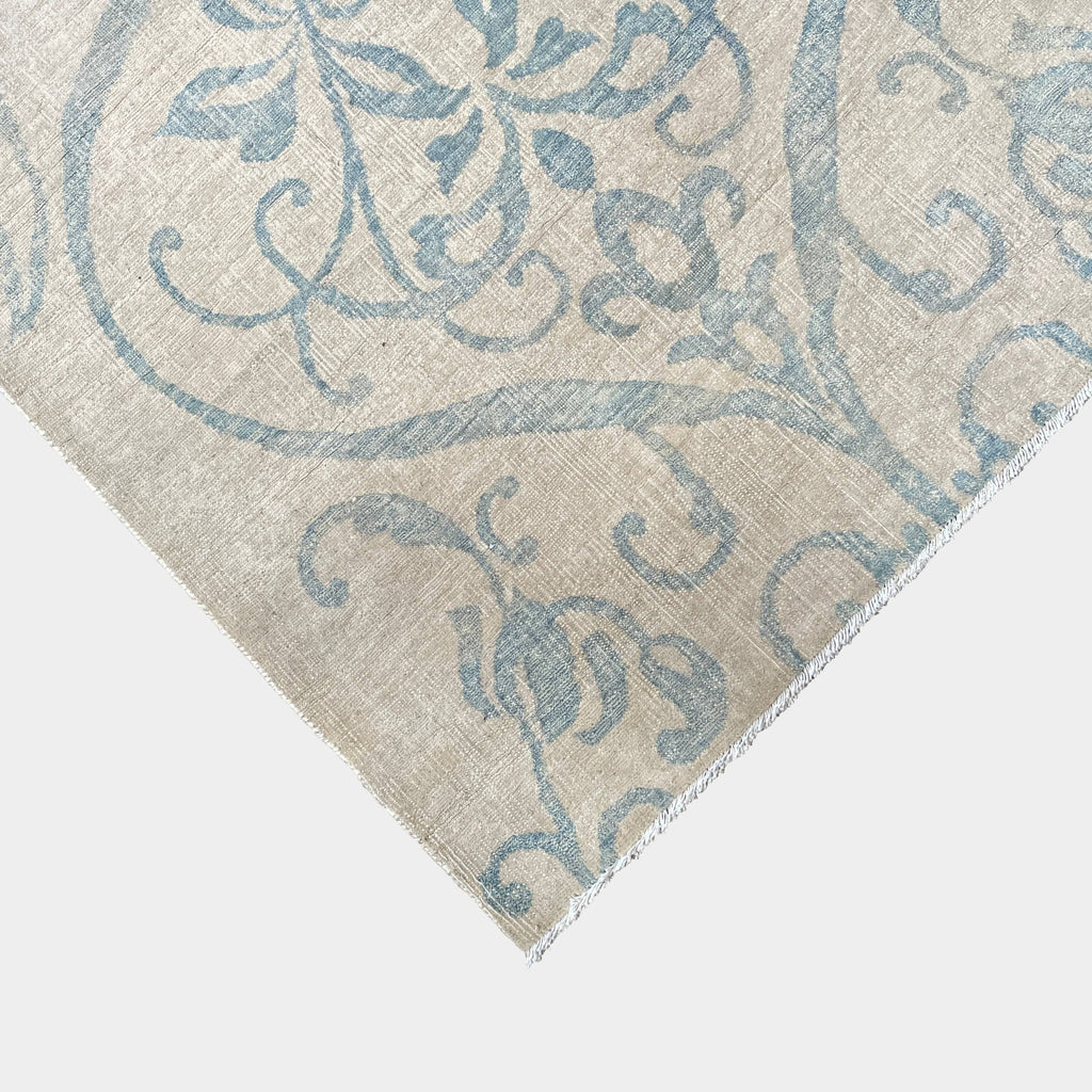 Close-up of a corner of an ornate, traditional Vintage rug with blue patterns on a beige background.