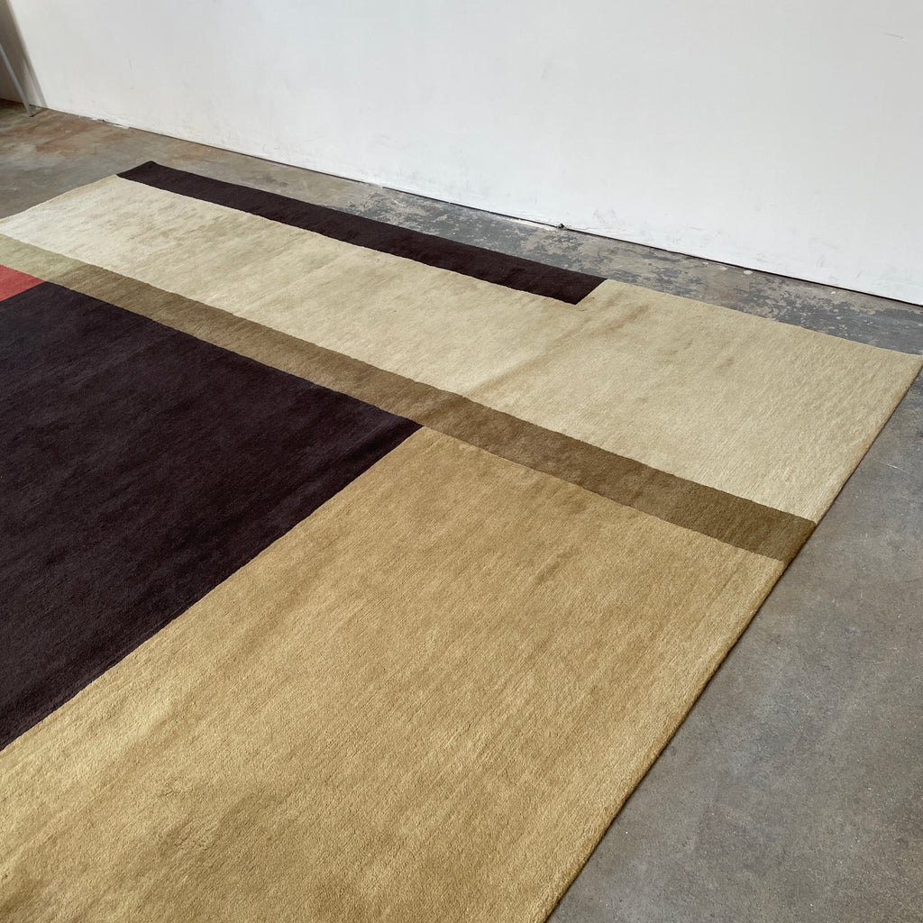 A Delinear wool rug featuring blocks of color in shades of brown, beige, and black with varying saturation and size, creating a minimalist and modern design.