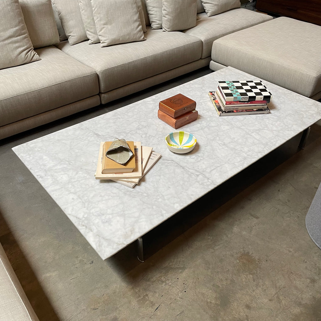 Low rectangular marble B&B Italia Diesis coffee table with thin black metal legs, isolated on a white background.