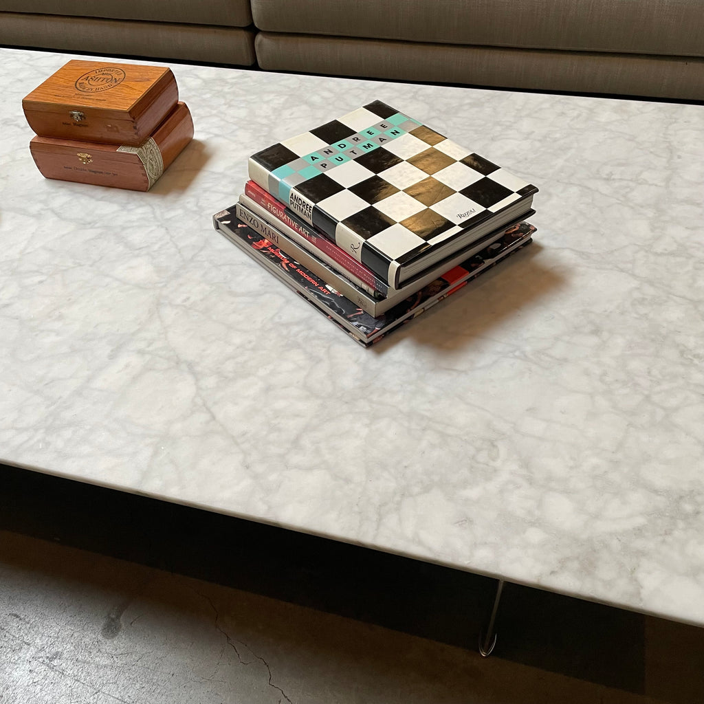 Low rectangular marble B&B Italia Diesis coffee table with thin black metal legs, isolated on a white background.