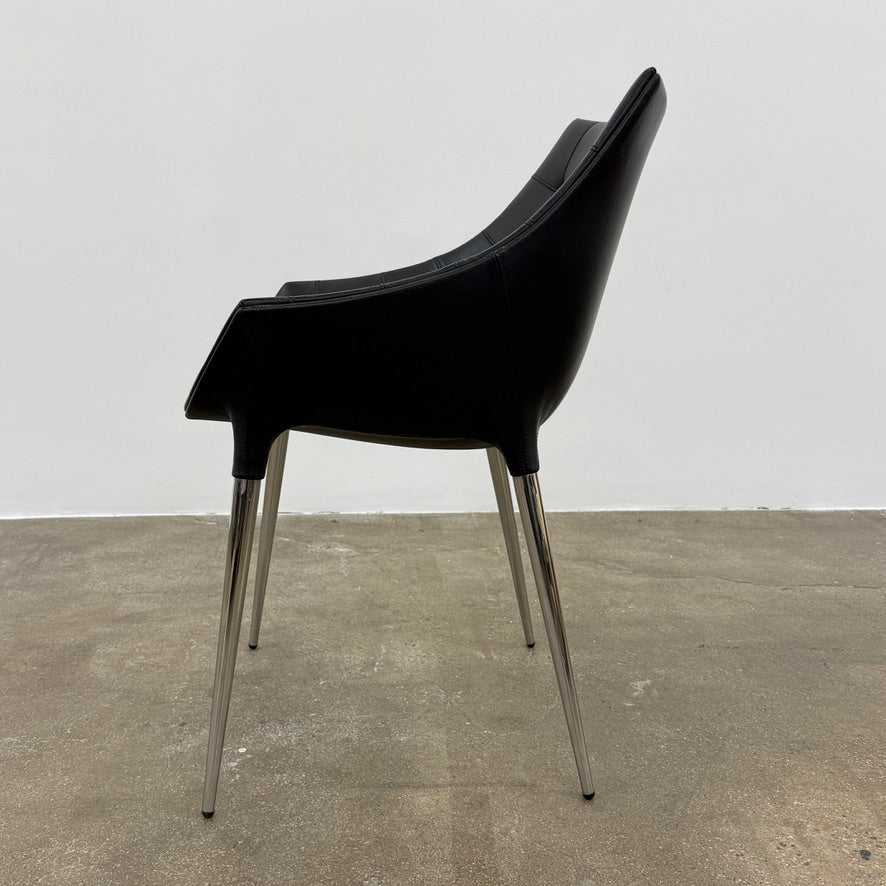 The Cassina Passion Side Chair by Cassina is a modern black upholstered chair with a curved backrest, button detailing, and four sleek metal legs inspired by the Passion design.