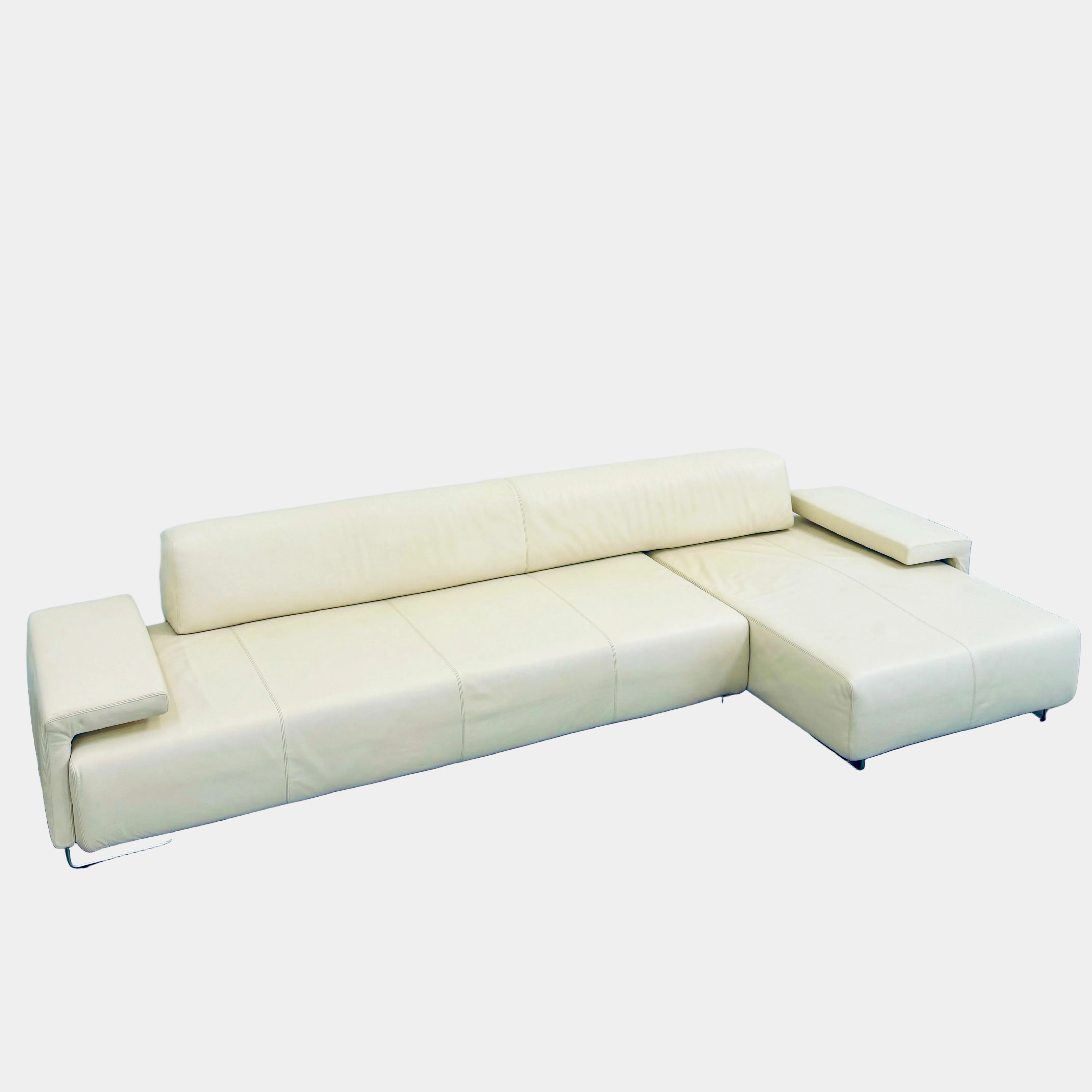 A Moroso Lowland Sectional Sofa in bone leather, with a right chaise lounge, stands on a bare concrete floor against a plain light wall.
