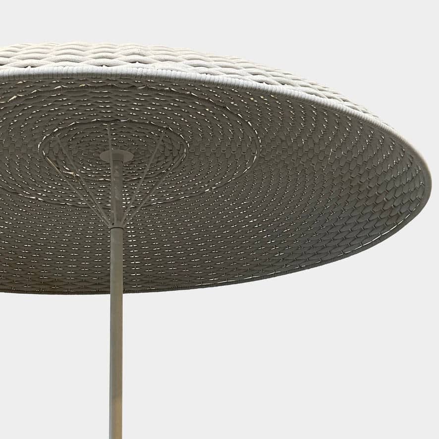 A Paola Lenti Mogambo Parasol on a white stand, designed by Paola Lenti.
