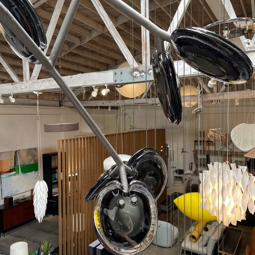 The Bocci Armature Chandelier T16.17aA1 by Bocci features multiple black branches with round, illuminated bulbs extending from a central base, offering a modern ceiling light fixture design inspired by contemporary aesthetics.