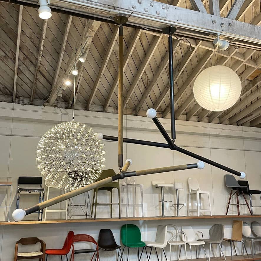 A large Apparatus Studio Suede Wrapped Arrow Ceiling Light featuring two metal rods and a glass globe, designed by Apparatus Studio.