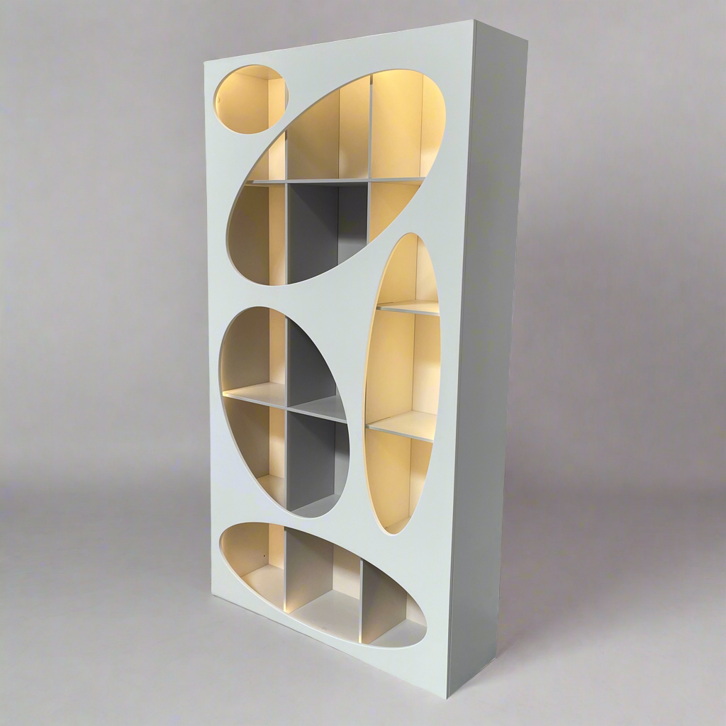 The Roche Bobois Denia Bookcase is a white bookshelf characterized by its abstract design, featuring multiple irregular oval cutouts, nine internal compartments, and integrated LED lighting, reminiscent of ROCHE BOBOIS styling.