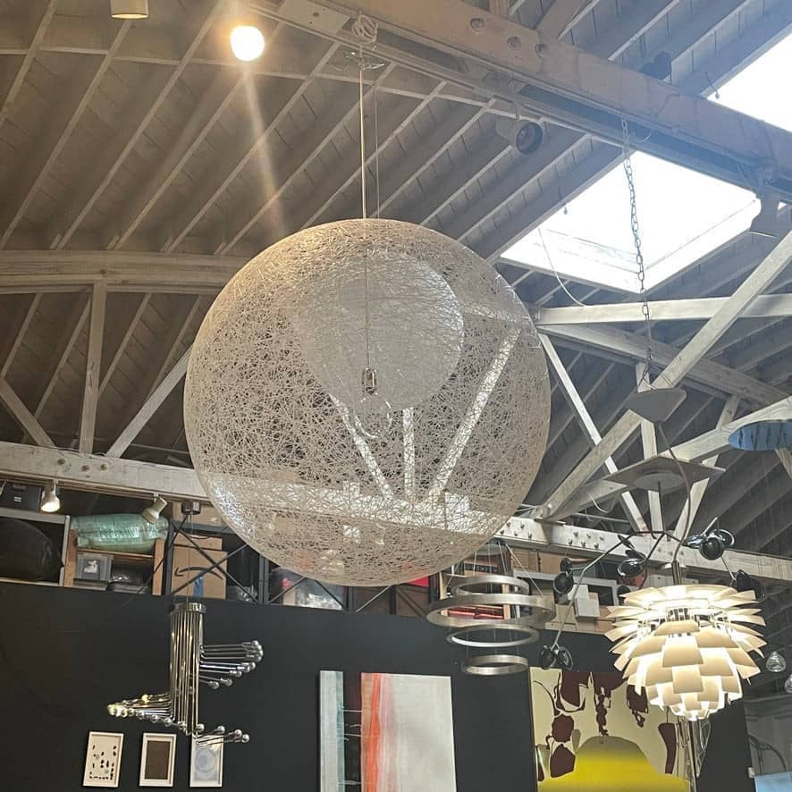 A Moooi Random Pendant suspension light with a white ball, reminiscent of the Moooi Random design, hanging from a light fixture.