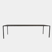 The Arco Slim Table by Arco is a minimalist rectangular table with a thin, flat surface and four slender legs, made from steel sandwich construction with a lightweight honeycomb core, shown against a plain white background.