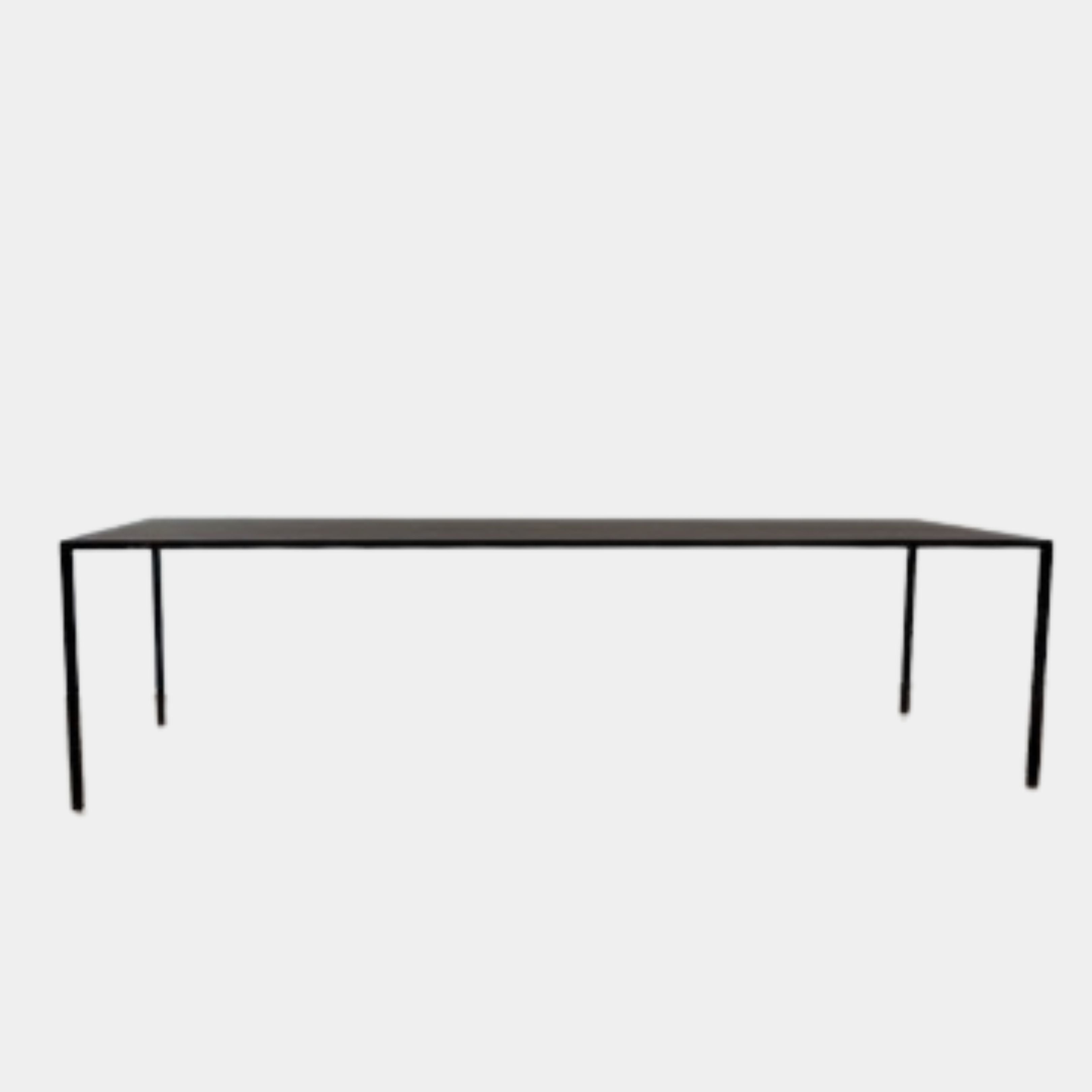 The Arco Slim Table by Arco is a minimalist rectangular table with a thin, flat surface and four slender legs, made from steel sandwich construction with a lightweight honeycomb core, shown against a plain white background.