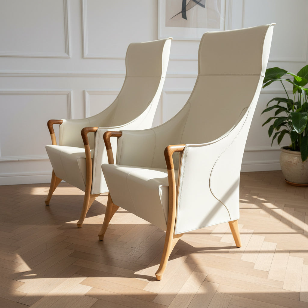 The Giorgetti “Progetti” Bergère / High-Back Lounge Chair by Giorgetti features light beige upholstery, wooden armrests and legs, and elegant ivory saddle leather accents, all inspired by the sophisticated Progetti collection, and is showcased against a plain white background.