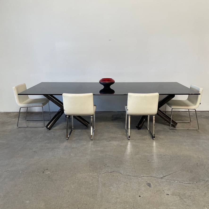 A luxurious Minotti Van Dyck Dining Table with black legs designed by Rodolfo Dordoni on a white background.
