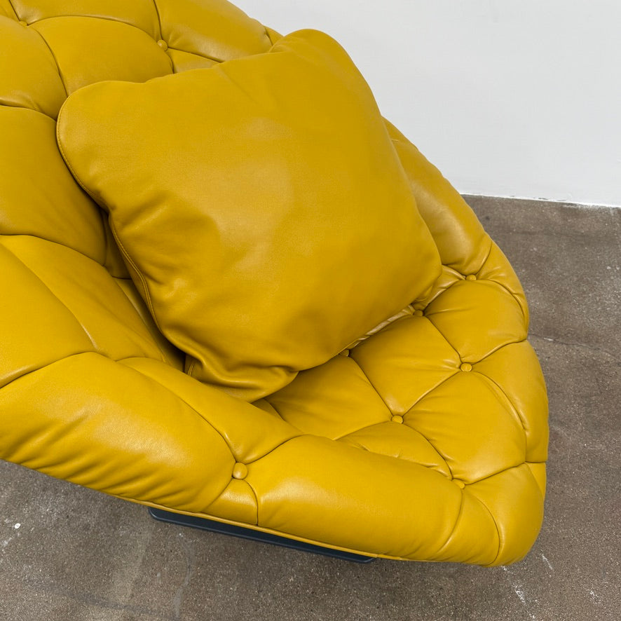 The Moroso Bohemian Low Armchair by Moroso features mustard yellow tufted leather upholstery, a matching cushion, and a black metal pedestal base, shown against a plain white background.