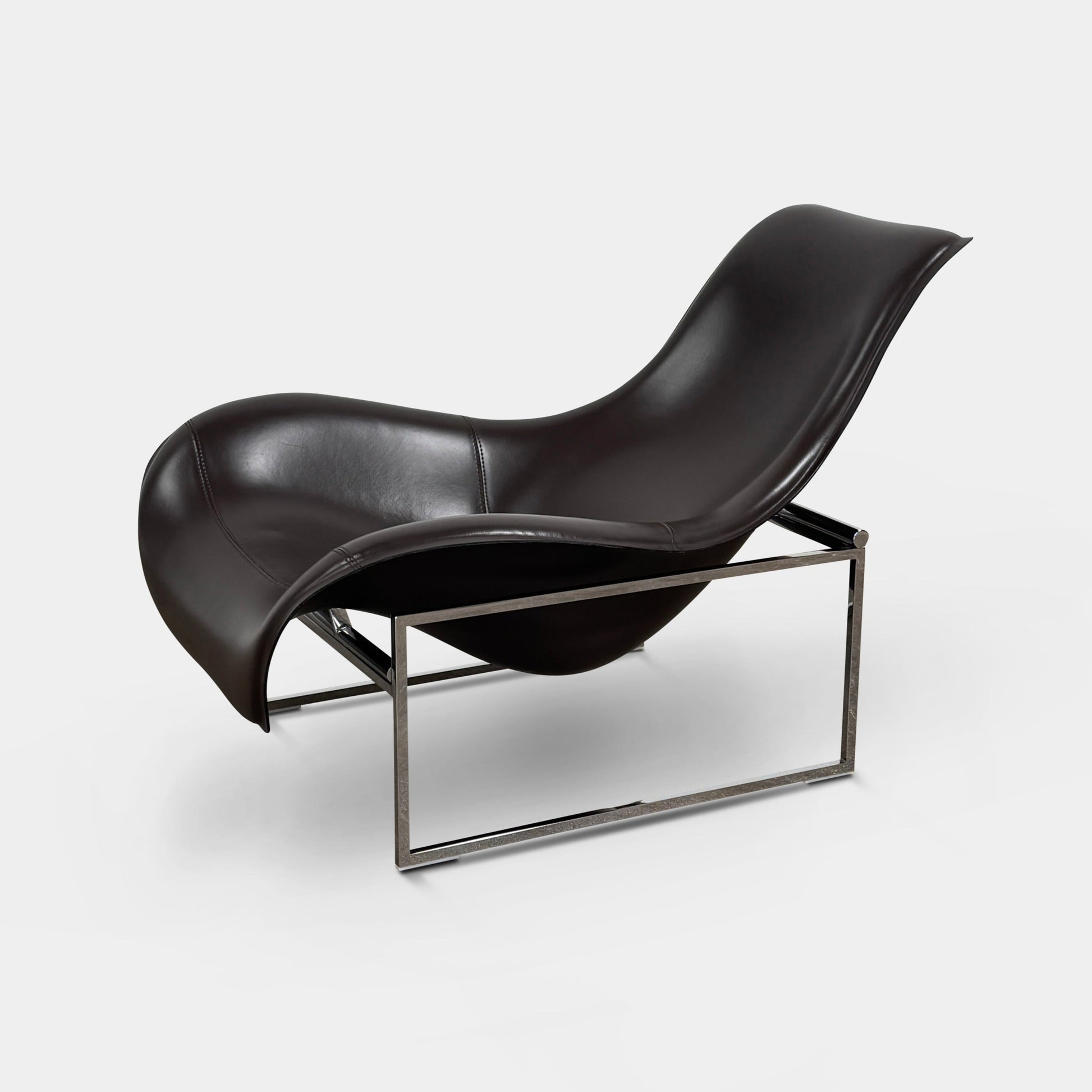 A B&B Italia Mart Relax Armchair with Tilting Mechanism in black saddle leather features a modern, curved design and is set on a polished concrete floor against a plain light gray wall.