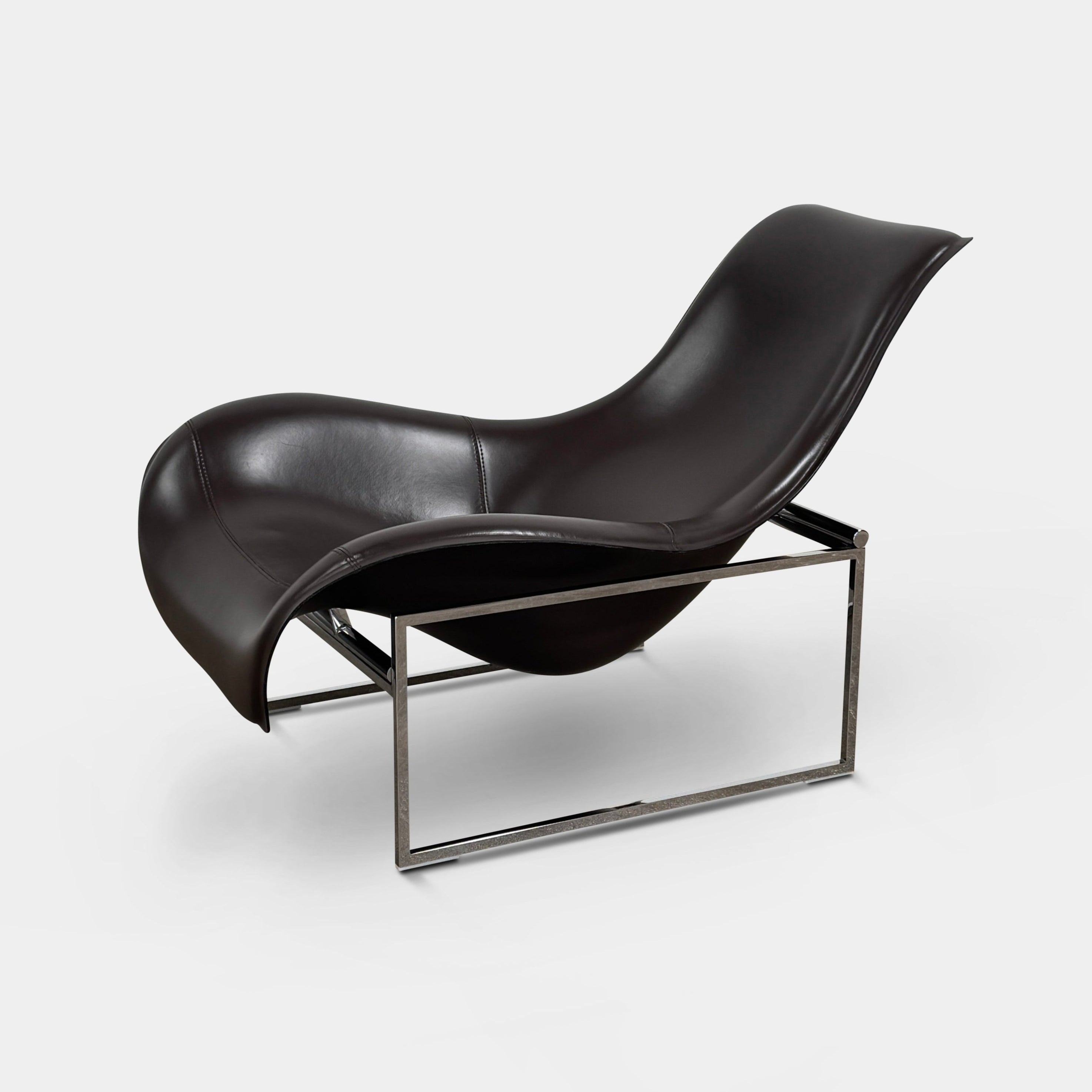 A B&B Italia Mart Relax Armchair with Tilting Mechanism in black saddle leather features a modern, curved design and is set on a polished concrete floor against a plain light gray wall.