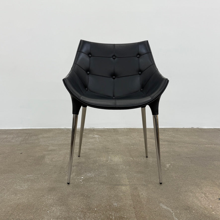 The Cassina Passion Side Chair by Cassina is a modern black upholstered chair with a curved backrest, button detailing, and four sleek metal legs inspired by the Passion design.