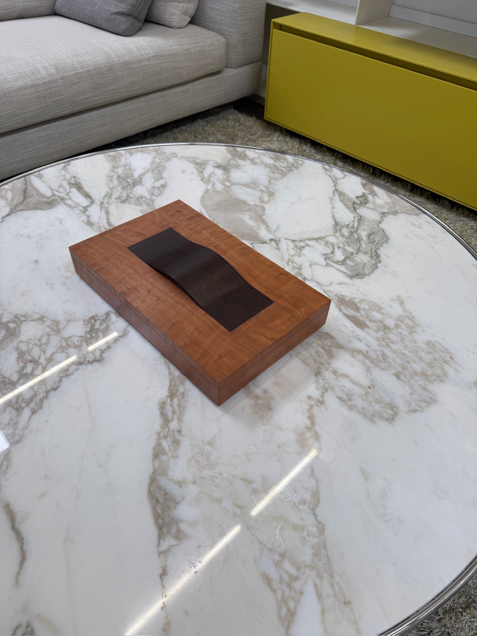 The Mike Fair Jewelry Box / Cigar Box by Mike Fair Custom Furnishings is a rectangular cherry wood box with a smooth finish and a curved, dark handle on the lid, displayed against a plain white background.