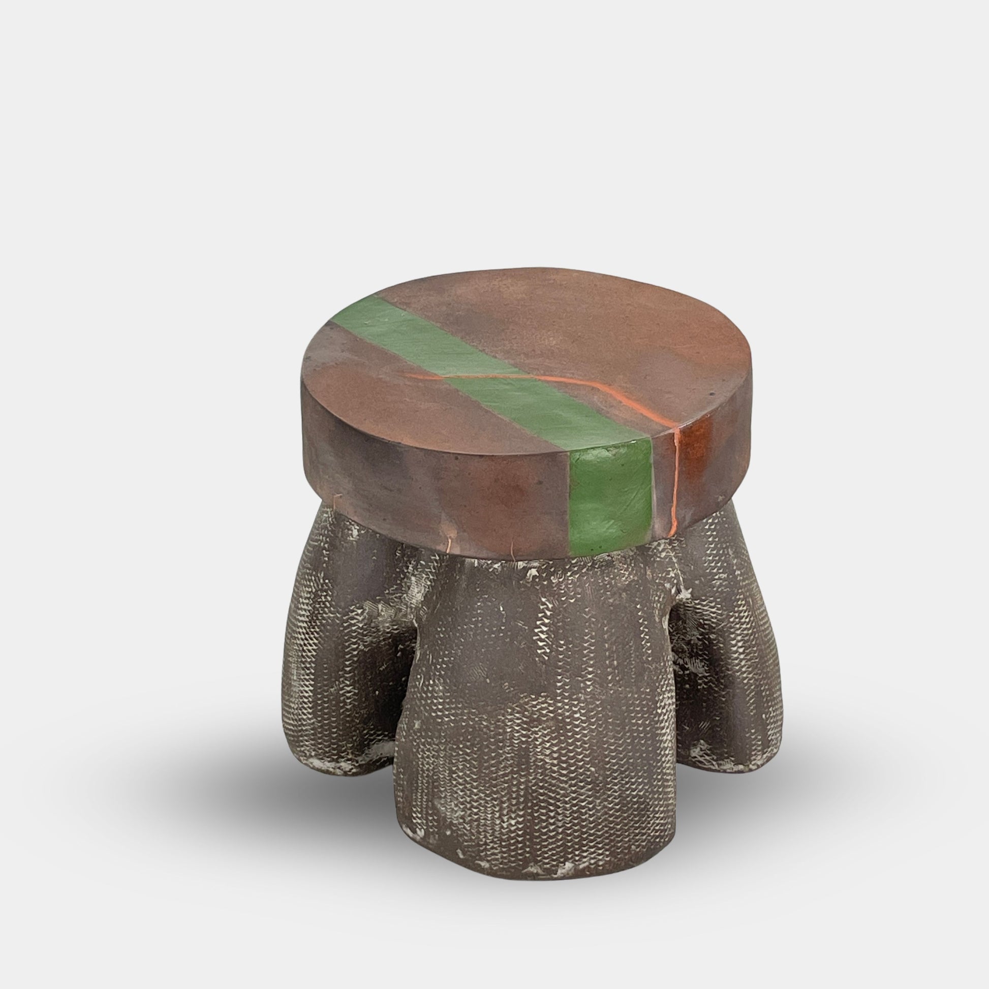 The Allyn Davis Mrs Beastie Ceramic Side Table by Artist features a round, textured design with a wooden top and green stripe. Its woven four-legged base subtly incorporates Kintsugo elements, adding depth and character to the piece.