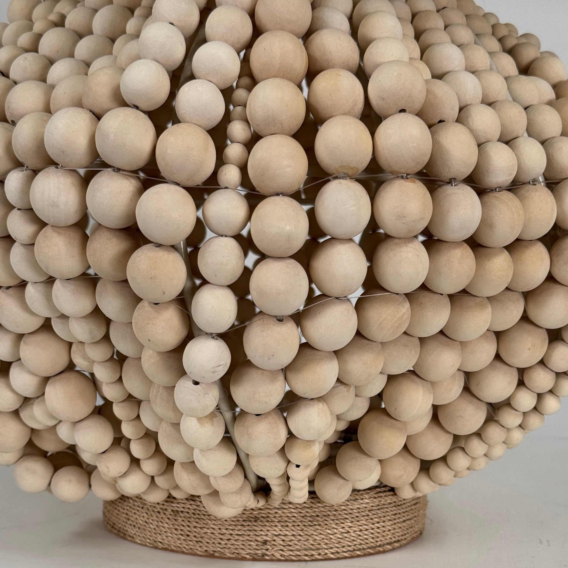 The Palecek Point Dume Table Lamp by Palecek features a clustered wooden bead base and a cylindrical beige fabric shade, offering relaxed coastal elegance for your space.