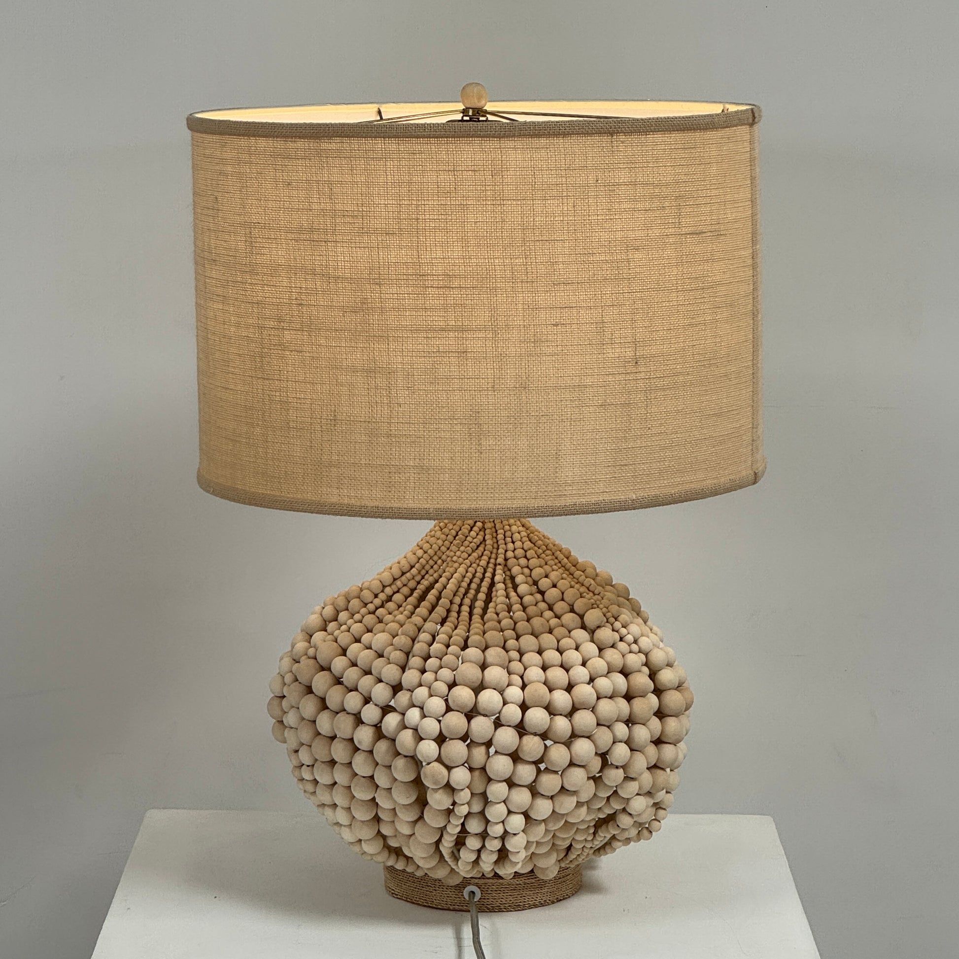 The Palecek Point Dume Table Lamp by Palecek features a clustered wooden bead base and a cylindrical beige fabric shade, offering relaxed coastal elegance for your space.