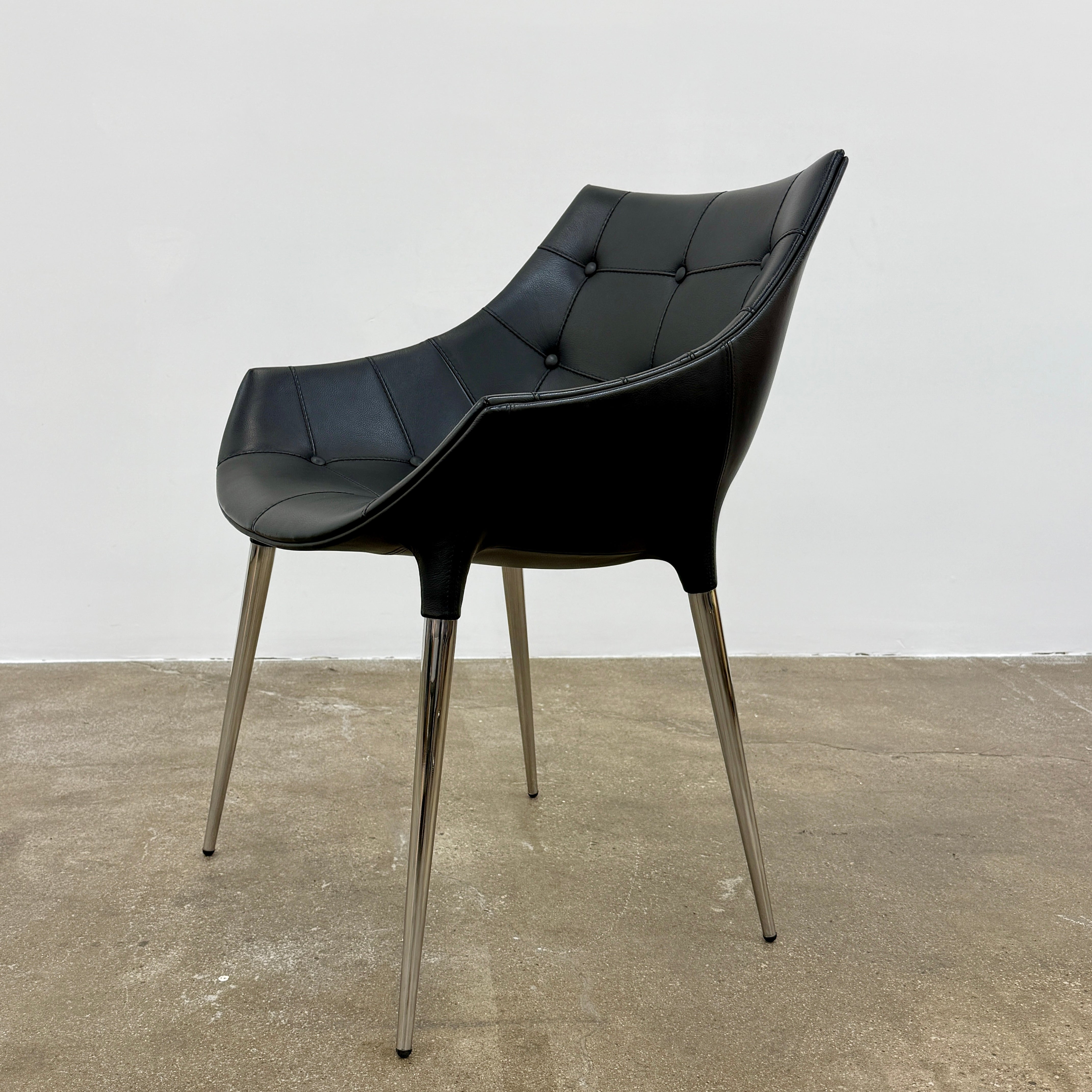 The Cassina Passion Side Chair by Cassina is a modern black upholstered chair with a curved backrest, button detailing, and four sleek metal legs inspired by the Passion design.