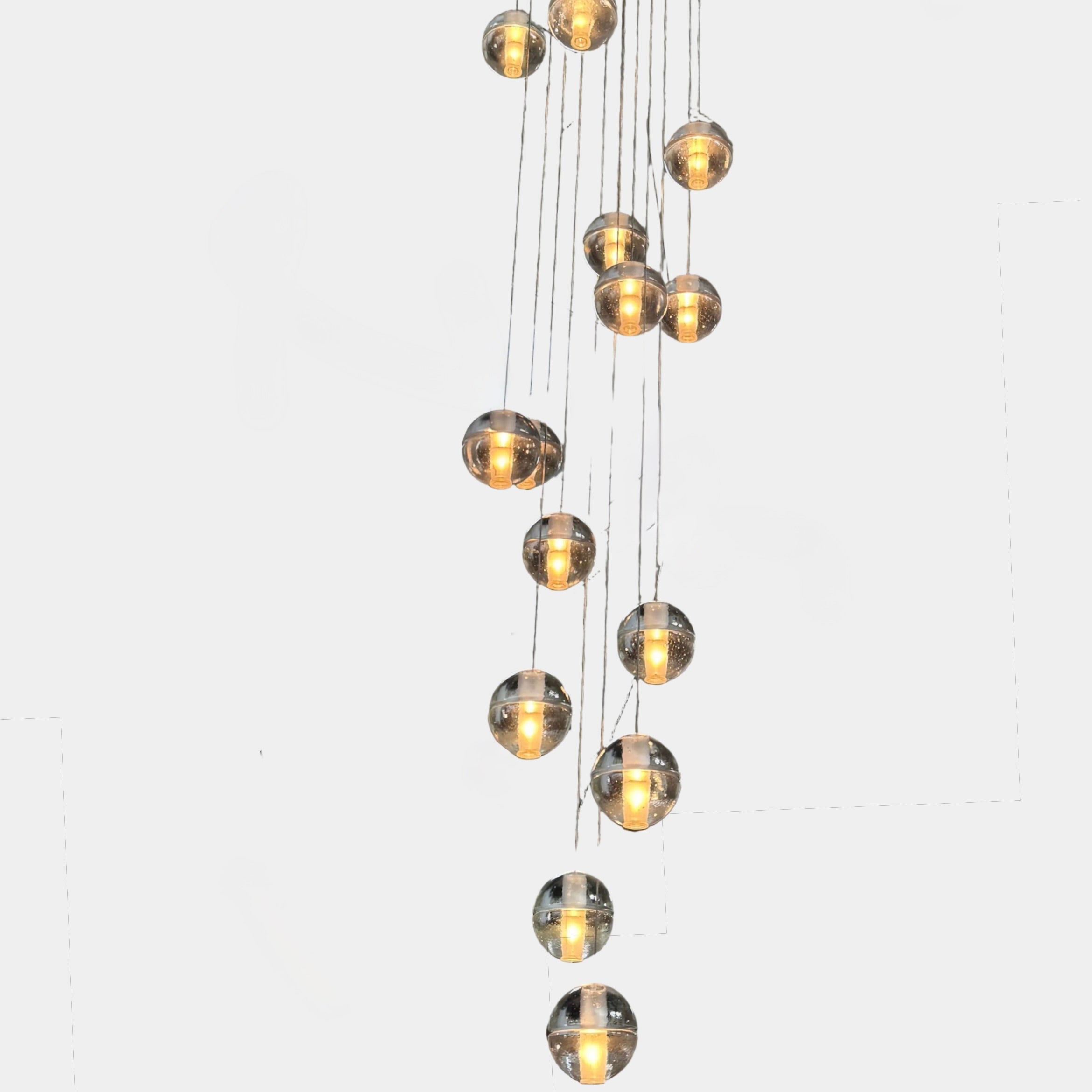 The Bocci 14.14 Pendant Chandelier by Bocci features a vertical cluster of metallic pendants, each with a glowing bulb, suspended by thin cords against a white background for a modern look.