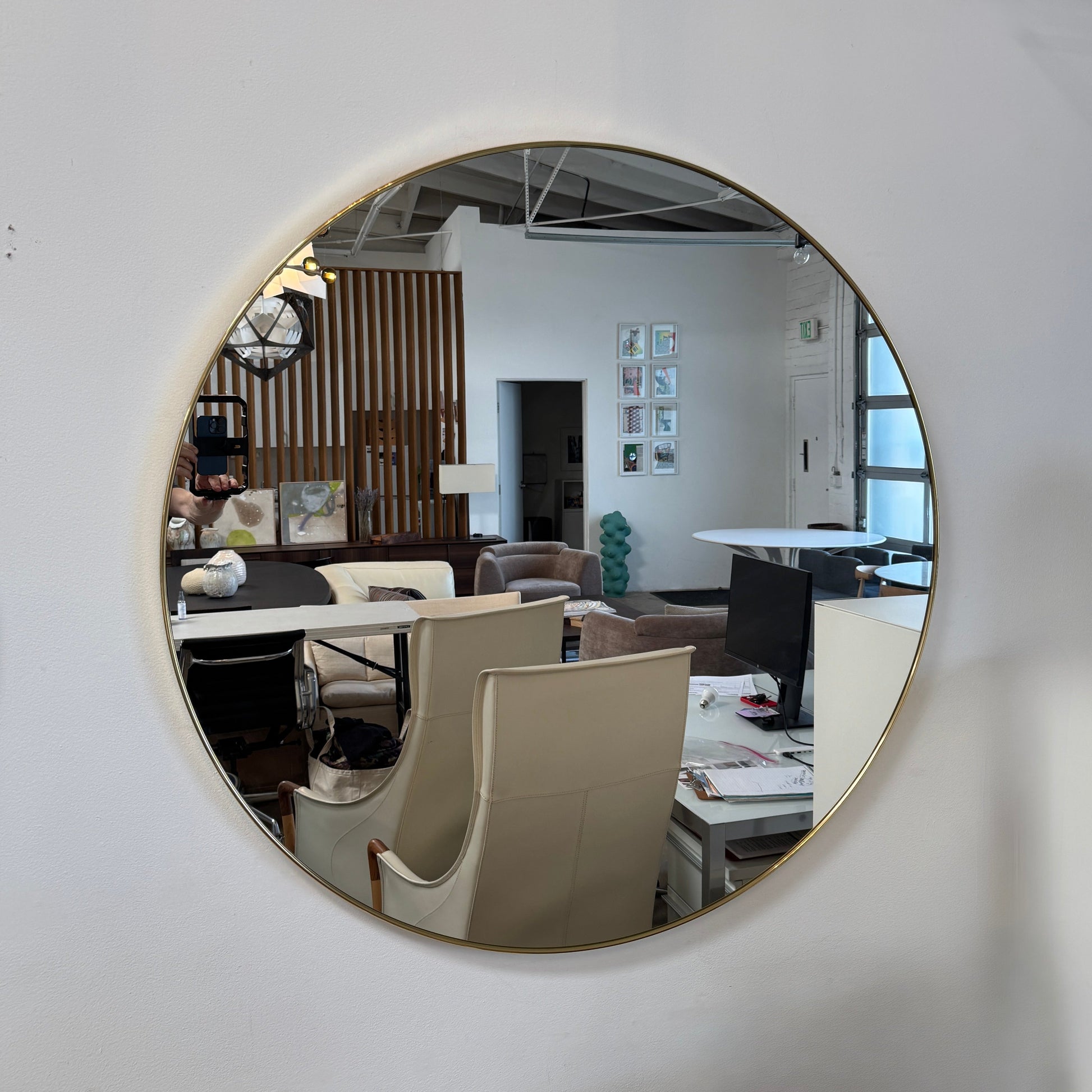 The Gubi 43″ Round Wall Mirror in Polished Brass, by Gubi, is displayed against a plain light gray background, showcasing its sleek and timeless design inspired by the iconic Gubi wall mirror.