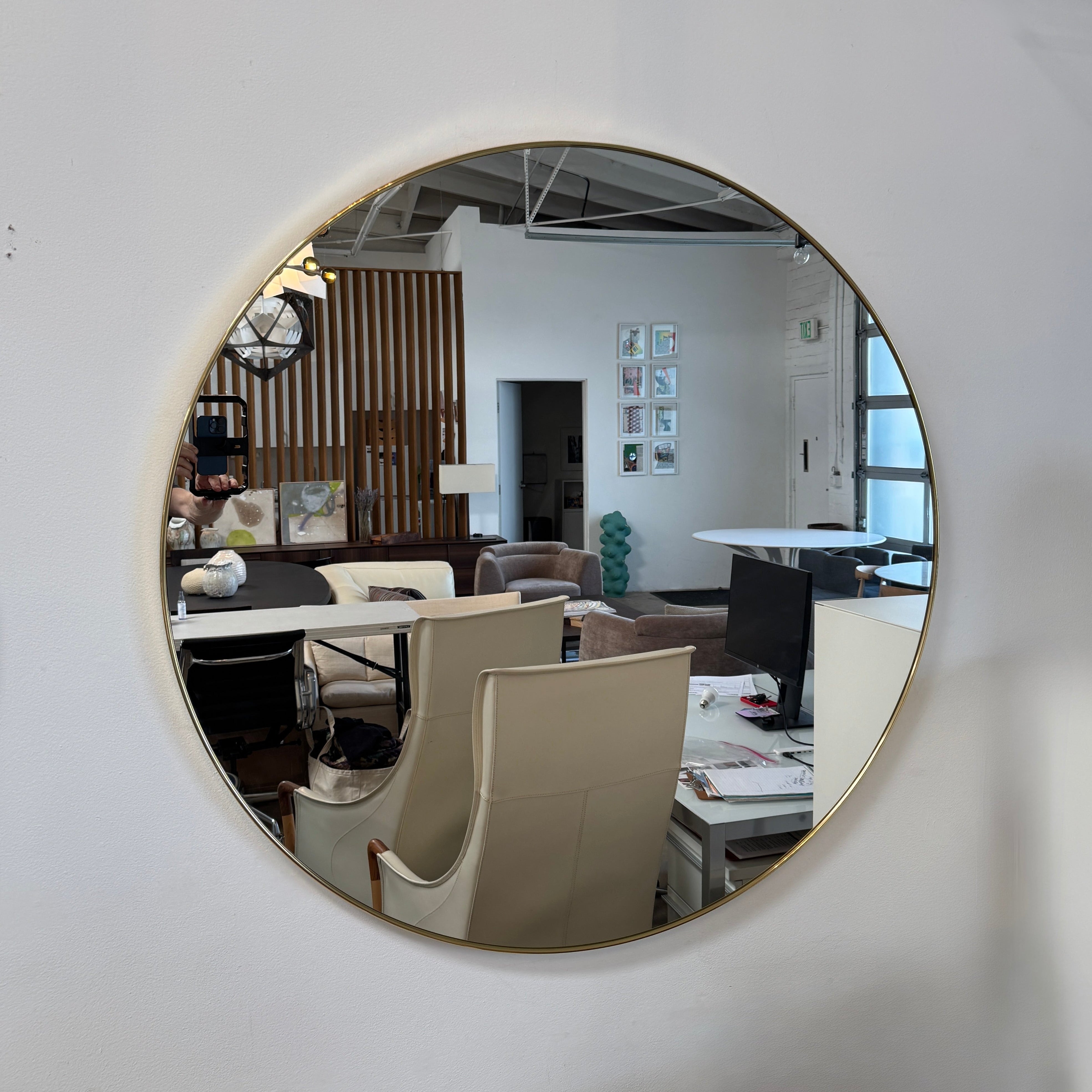 The Gubi 43″ Round Wall Mirror in Polished Brass, by Gubi, is displayed against a plain light gray background, showcasing its sleek and timeless design inspired by the iconic Gubi wall mirror.