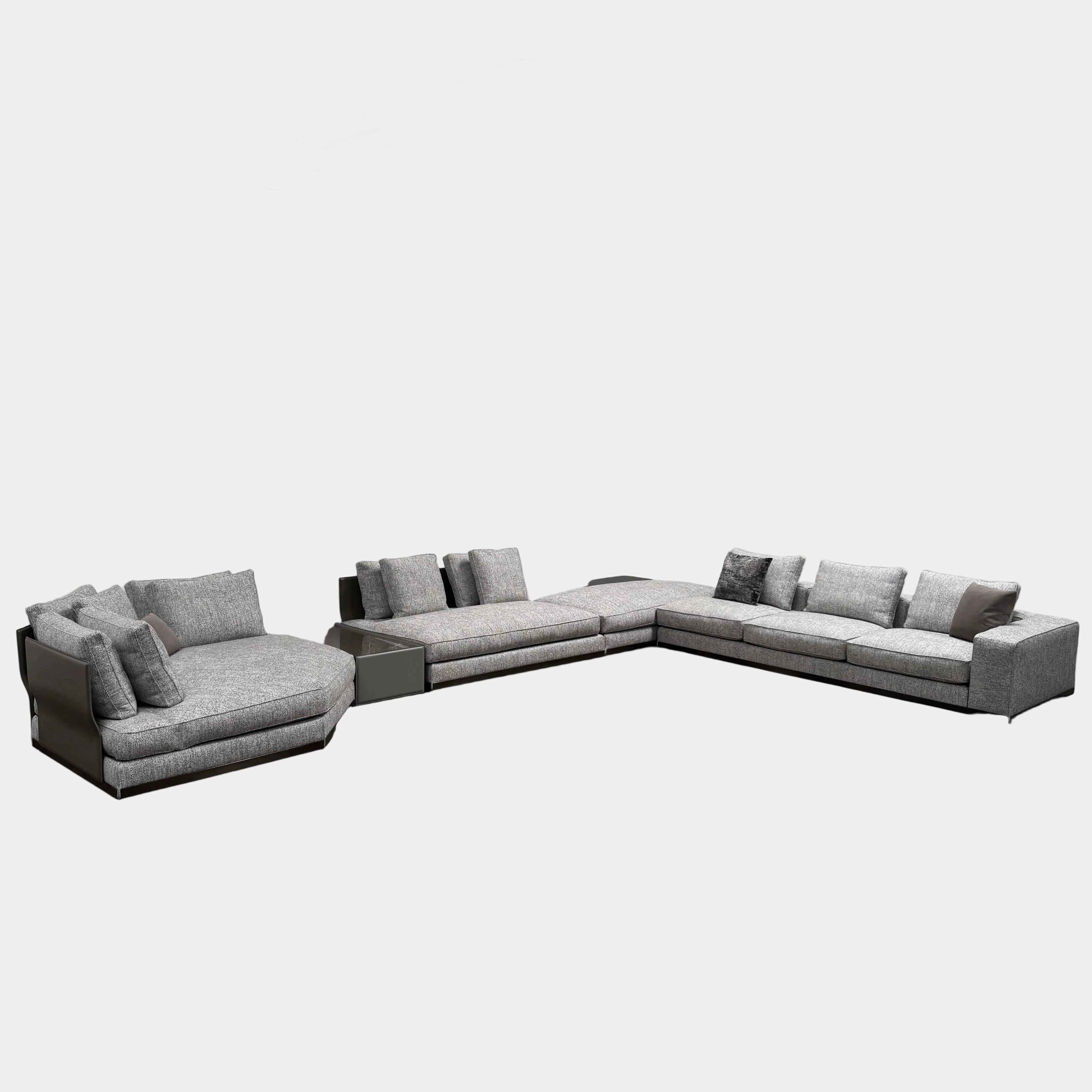 The Minotti West Sectional Sofa with Side Table and Clive Bench by Minotti features a large, L-shaped modern design with gray upholstery, multiple plush cushions, and an integrated side table—perfect for elevating luxury living rooms—all set against a plain white background.