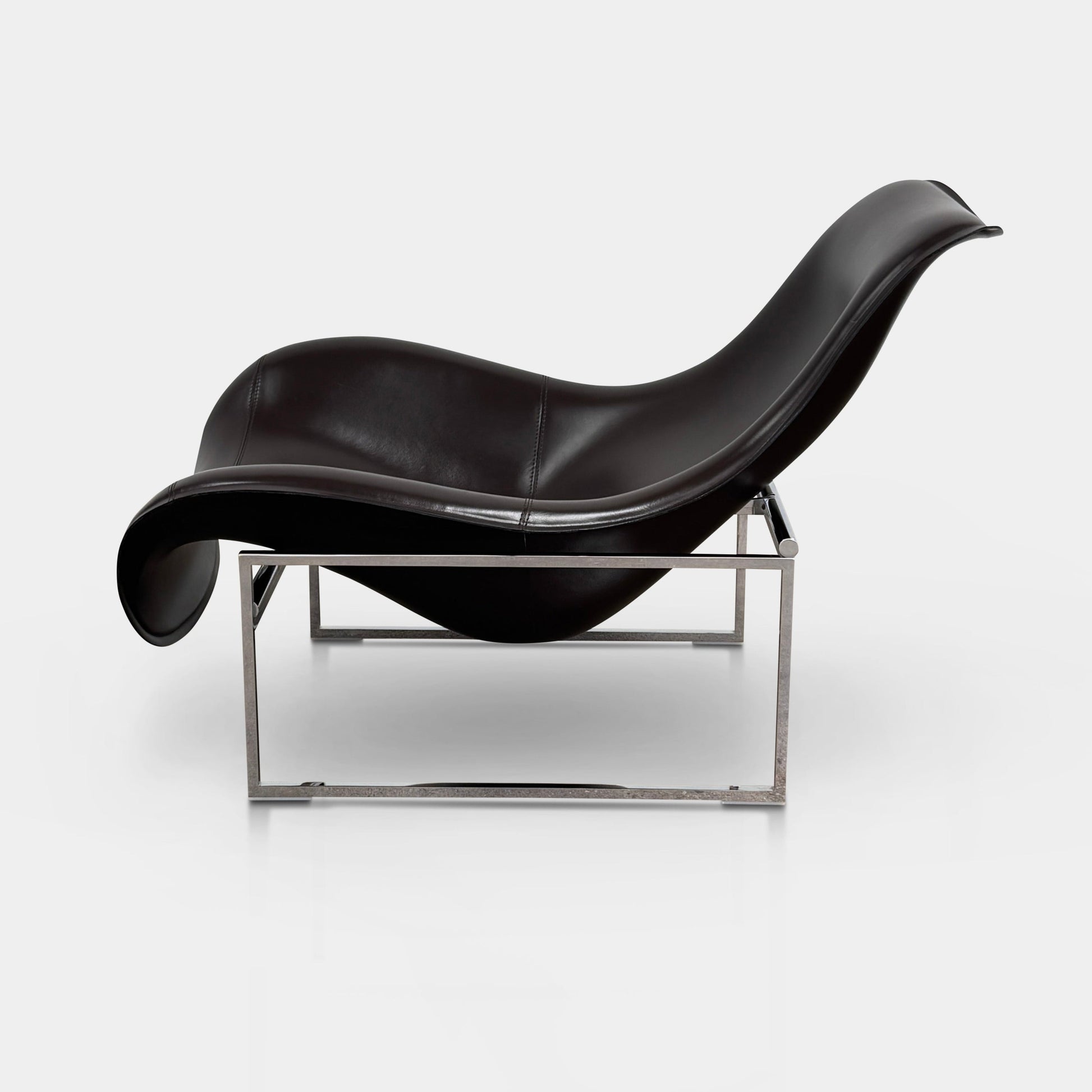 A B&B Italia Mart Relax Armchair with Tilting Mechanism in black saddle leather features a modern, curved design and is set on a polished concrete floor against a plain light gray wall.