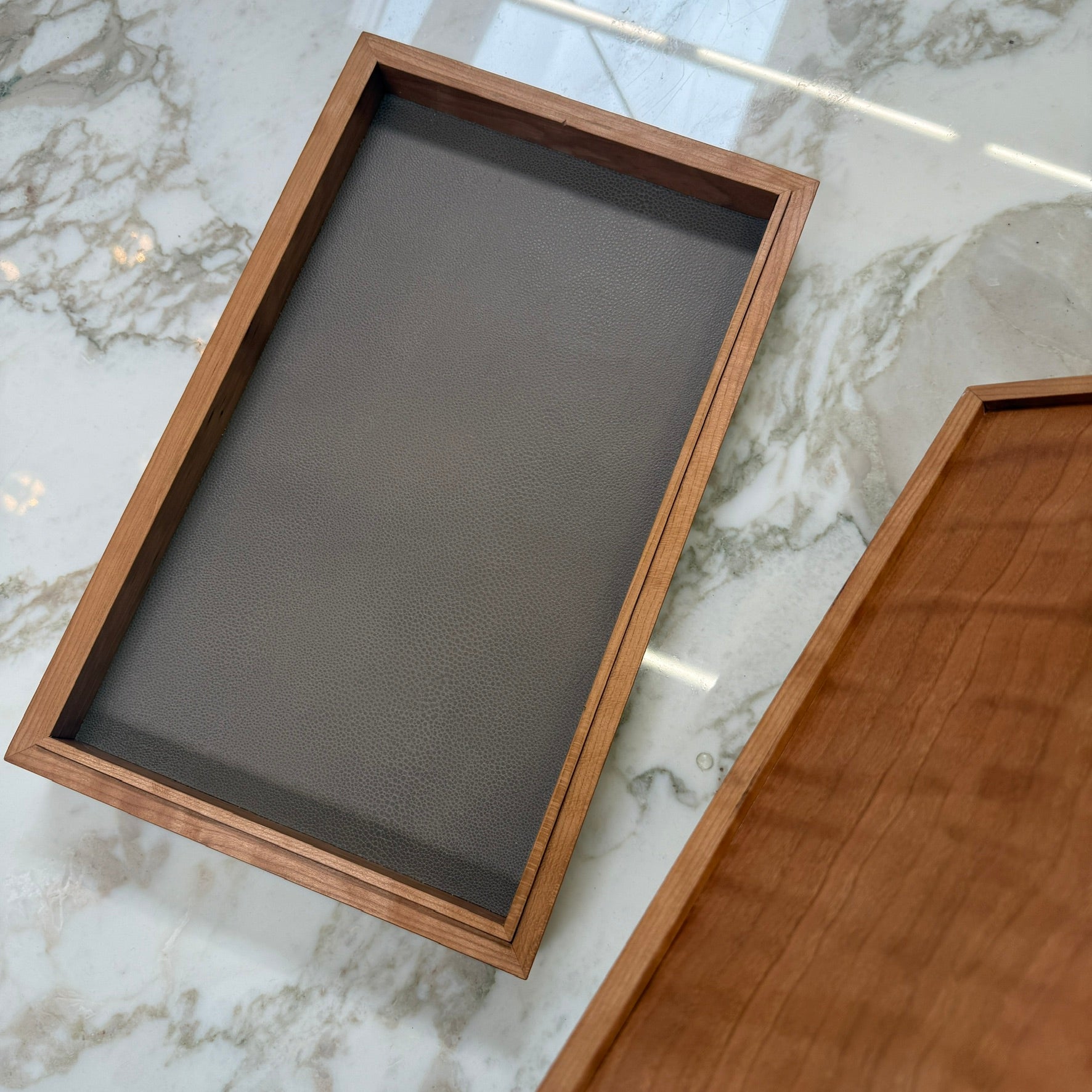 The Mike Fair Jewelry Box / Cigar Box by Mike Fair Custom Furnishings is a rectangular cherry wood box with a smooth finish and a curved, dark handle on the lid, displayed against a plain white background.