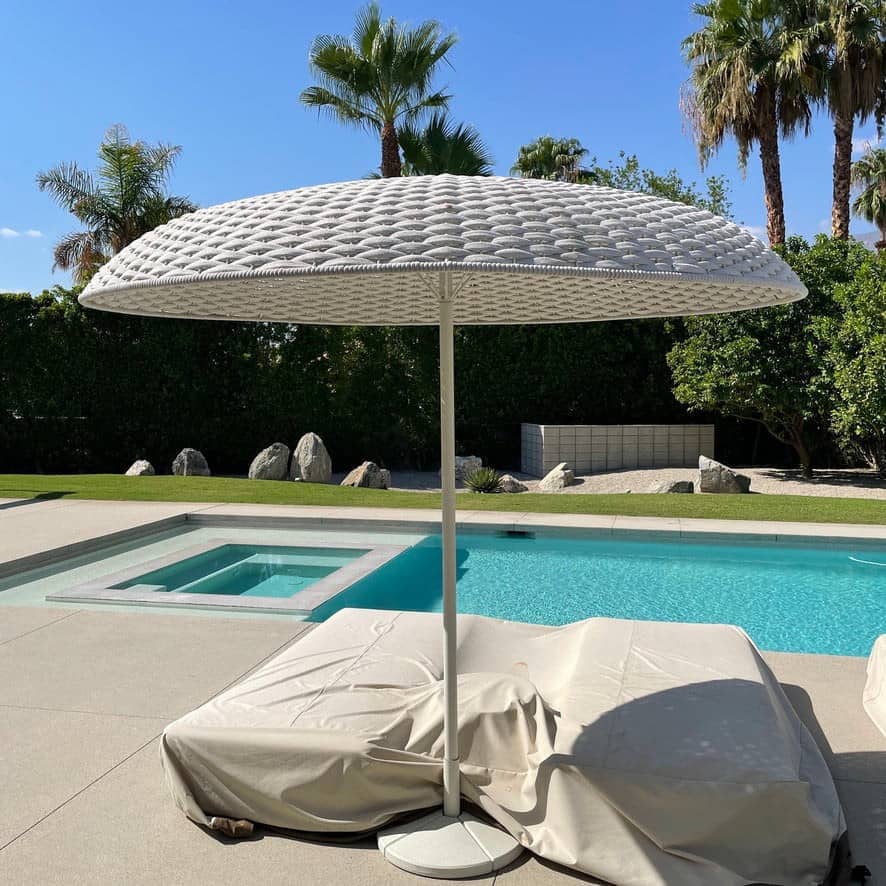 A Paola Lenti Mogambo Parasol on a white stand, designed by Paola Lenti.