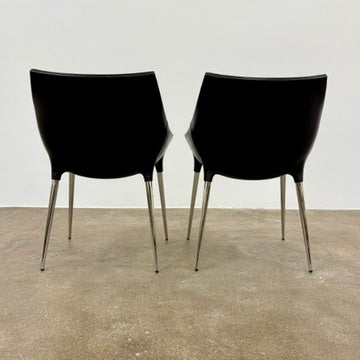 The Cassina Passion Side Chair by Cassina is a modern black upholstered chair with a curved backrest, button detailing, and four sleek metal legs inspired by the Passion design.