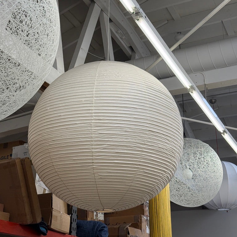 The Noguchi Akari 120A Suspension Lamp by Noguchi, a round beige paper lantern with horizontal ribbing, hangs against a plain white background, showcasing the timeless elegance of Japanese craftsmanship.