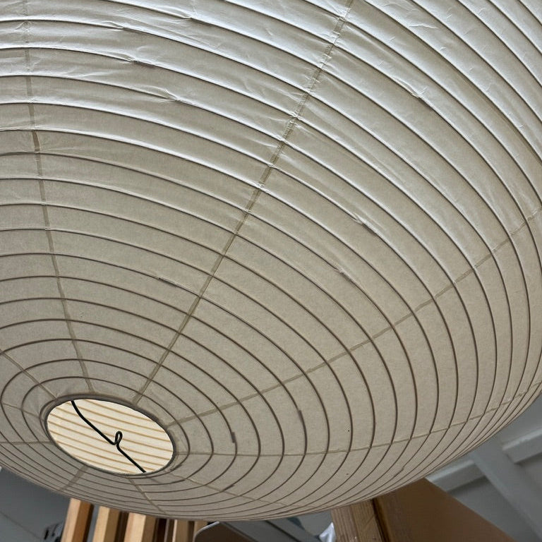 The Noguchi Akari 120A Suspension Lamp by Noguchi, a round beige paper lantern with horizontal ribbing, hangs against a plain white background, showcasing the timeless elegance of Japanese craftsmanship.