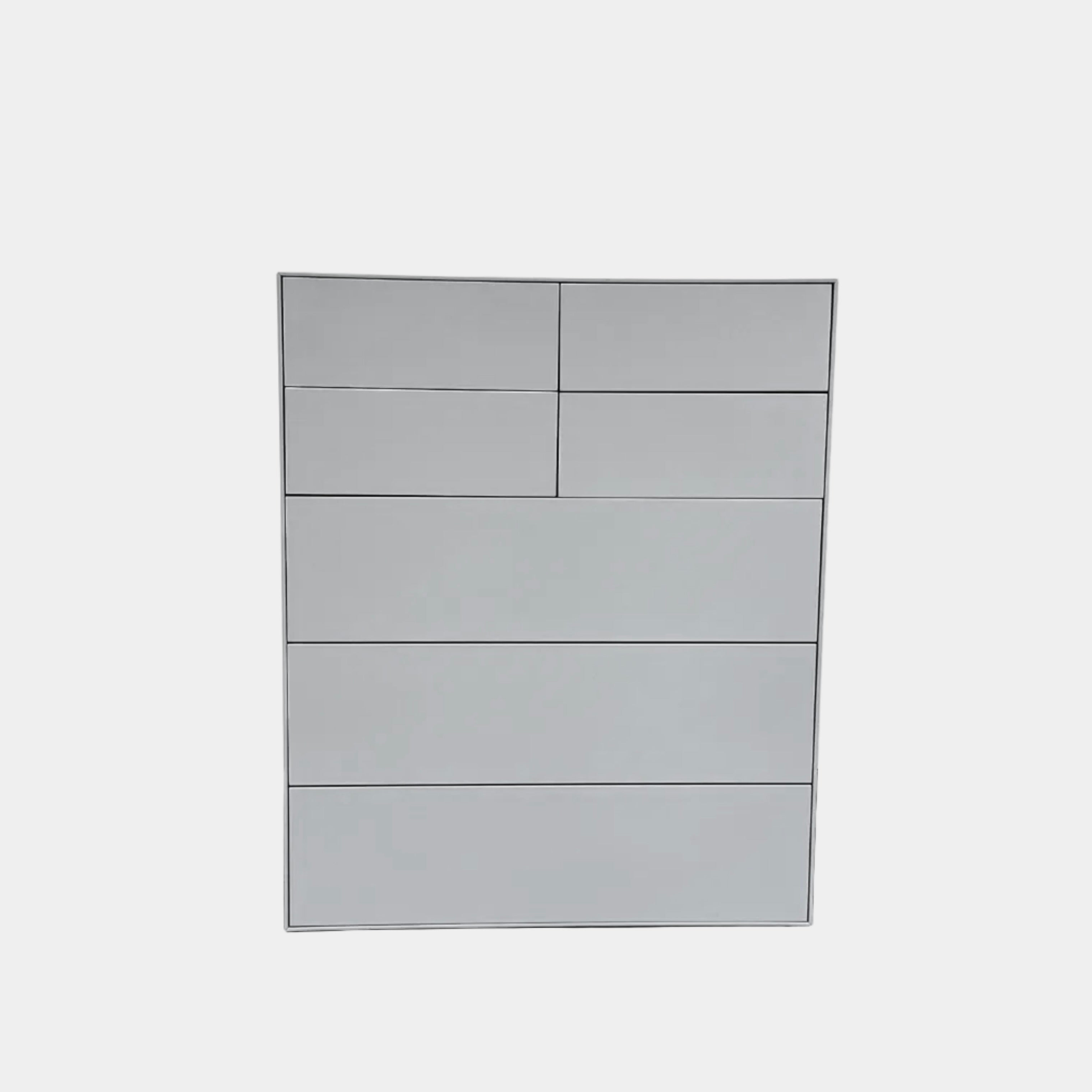 The Treku Lauki Tall Dresser by Treku, with a sleek lacquered finish and push-latch drawers—one partially open—stands on a concrete floor against a plain white wall.