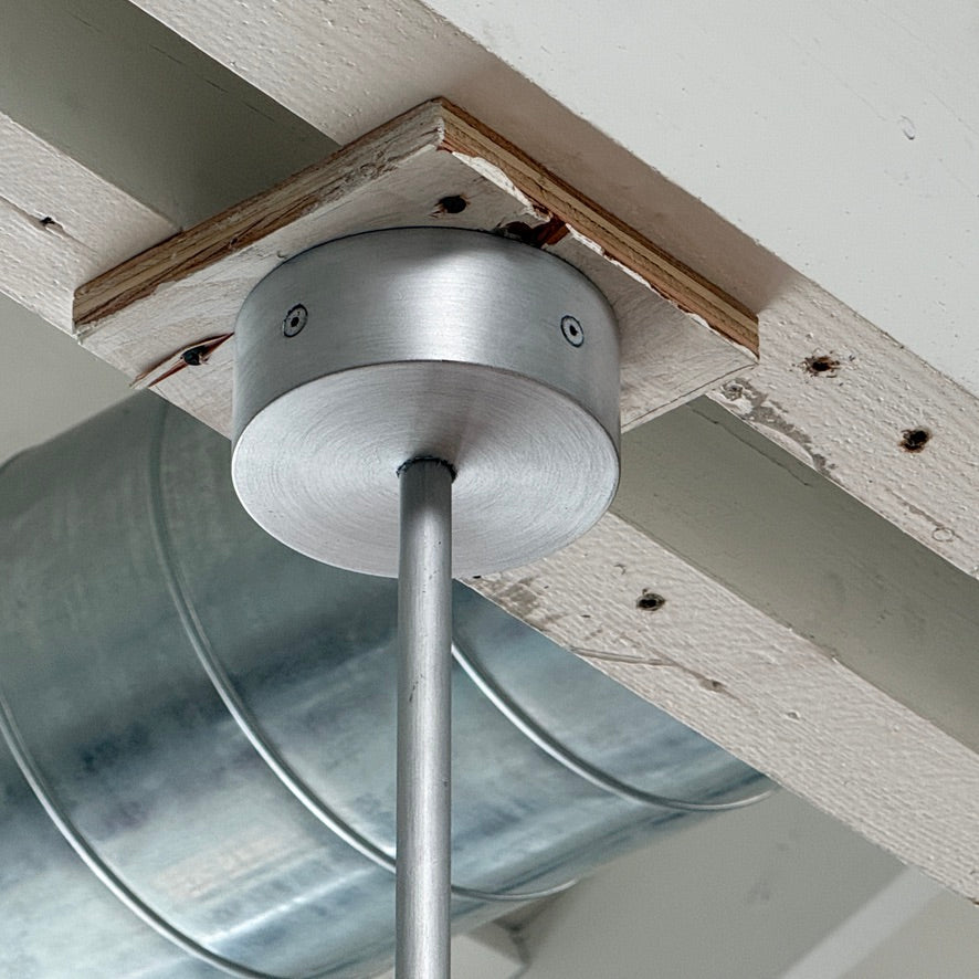 The Pouenat Last Night Branche Chandelier by Pouenat, featuring mouth-blown glass spheres, hangs beneath a white exposed beam ceiling with visible ductwork—an ideal statement for modern industrial interiors.