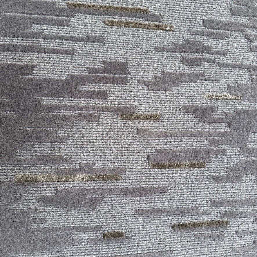 A close-up of the Kvadrat Multi-pile Wool and Silk Rug by Kvadrat, featuring an abstract linear pattern in light and dark gray wool and silk, displayed on a white background.