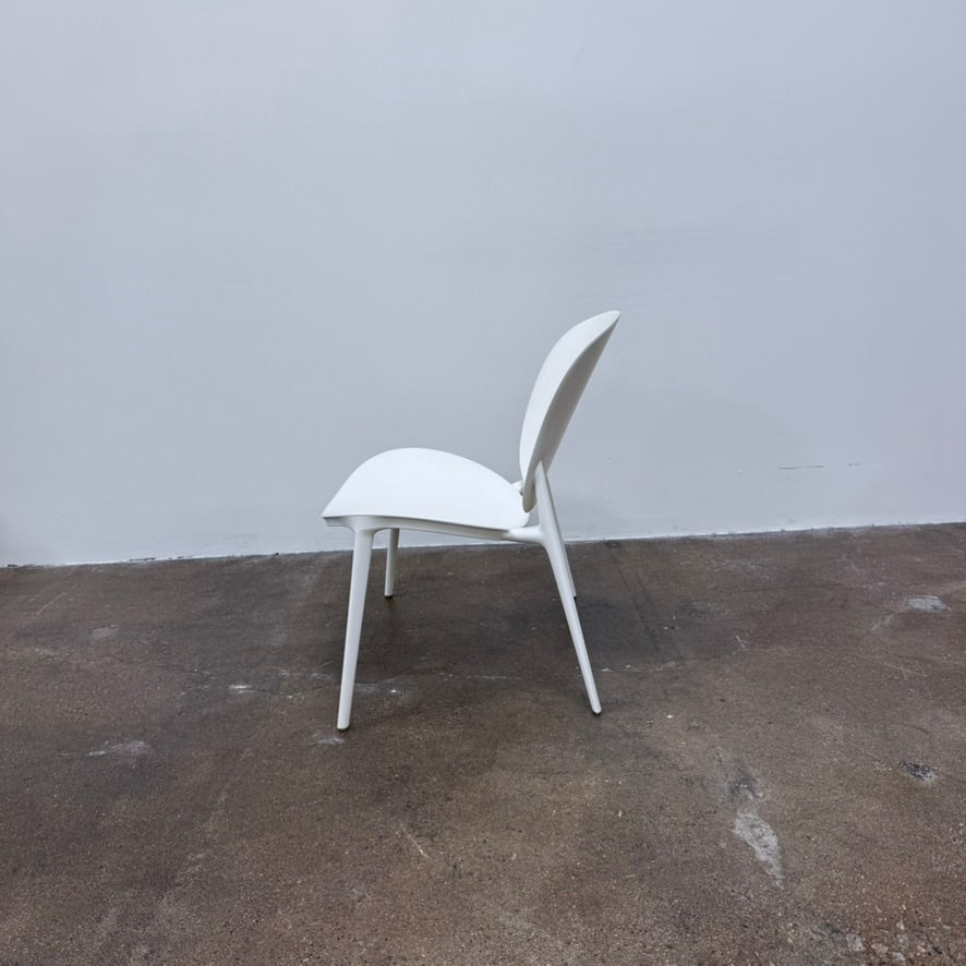 A white Kartell Be Bop lounge chair with a rounded backrest, tapered legs, and a weatherproof design for indoor or outdoor seating.