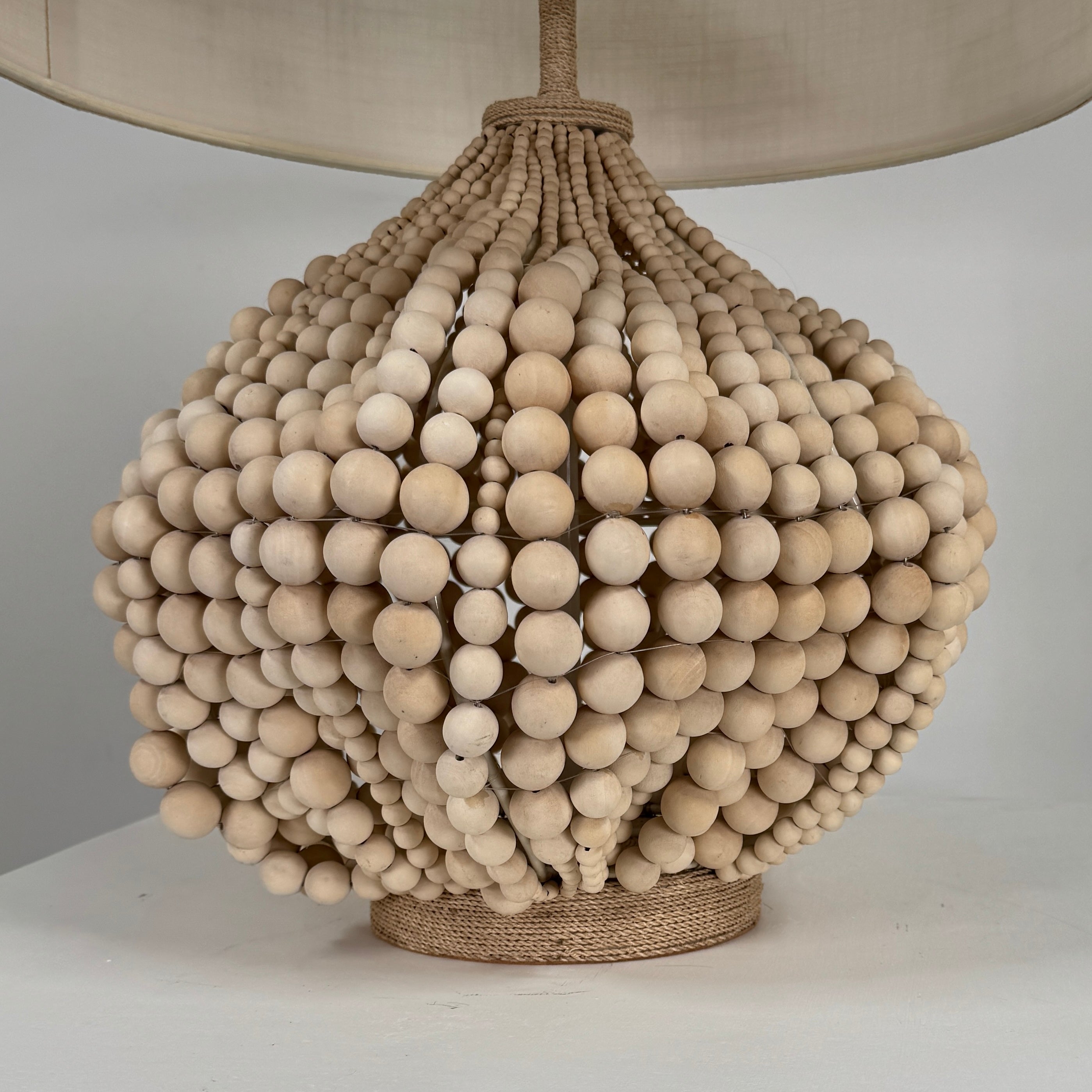 The Palecek Point Dume Table Lamp by Palecek features a clustered wooden bead base and a cylindrical beige fabric shade, offering relaxed coastal elegance for your space.