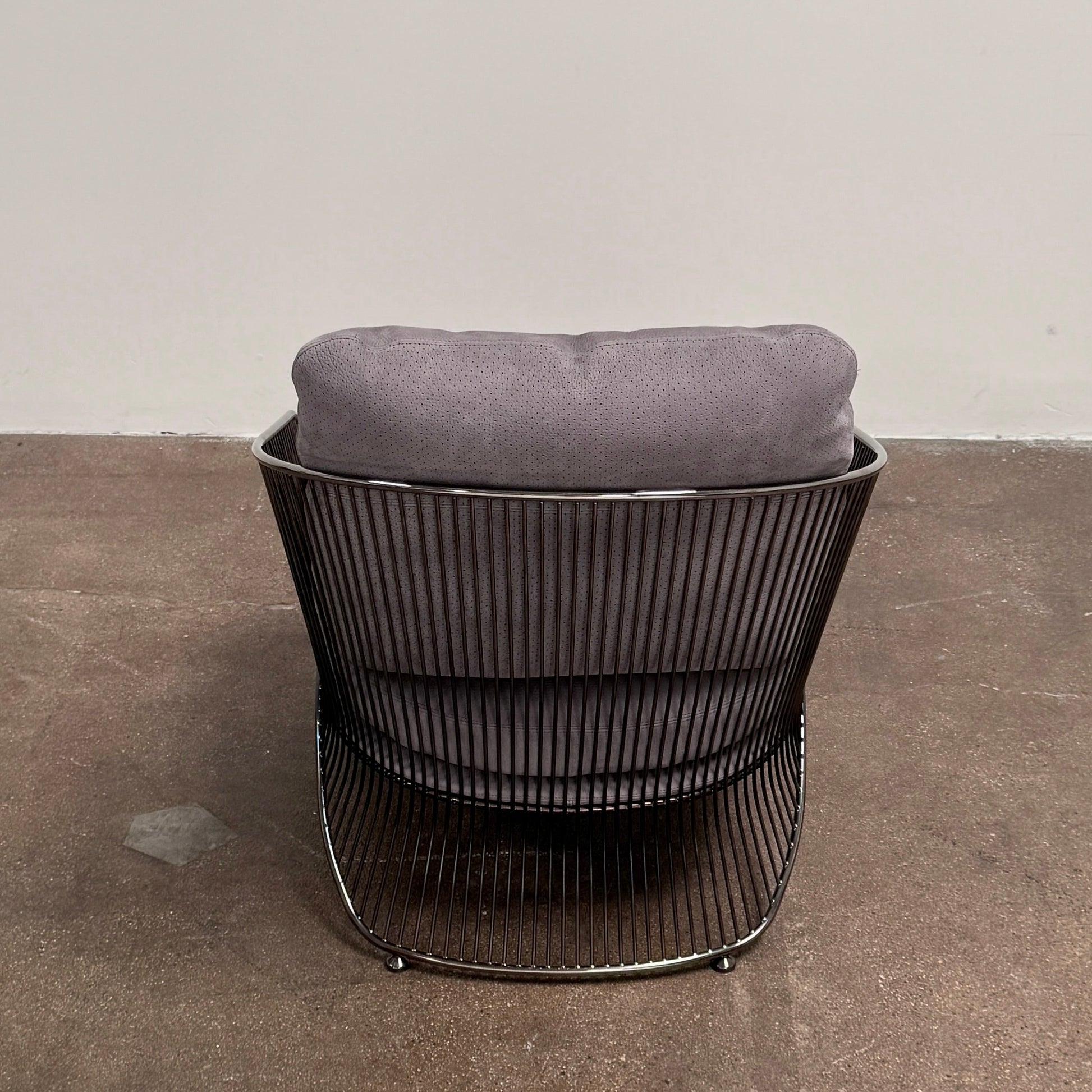 A set of two Minotti Colette Lounge Chairs by Minotti is displayed side by side against a plain white background. Each chair showcases luxurious gray nubuck leather upholstery and sleek black metal armrests, elegantly capturing the timeless mid-century silhouette characteristic of the iconic design.