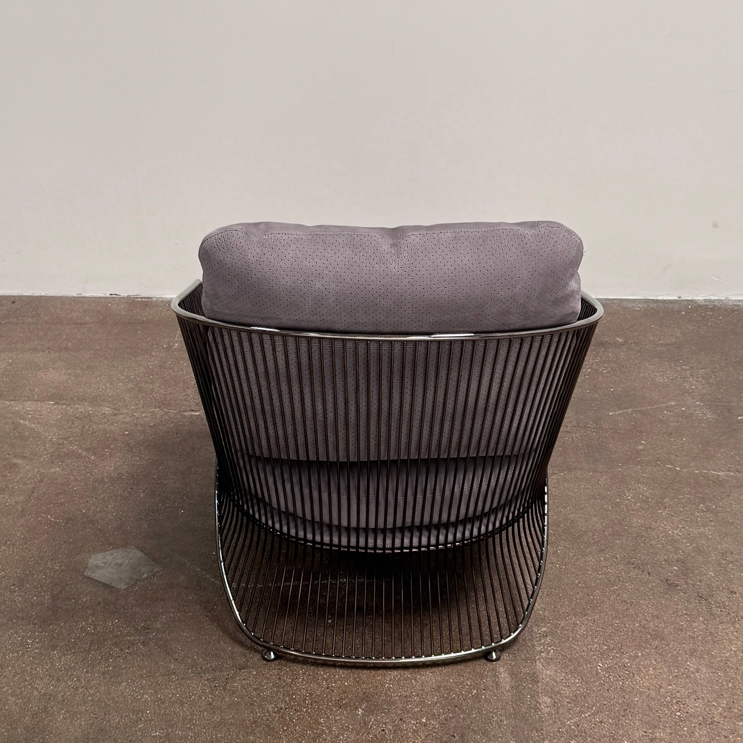 A set of two Minotti Colette Lounge Chairs by Minotti is displayed side by side against a plain white background. Each chair showcases luxurious gray nubuck leather upholstery and sleek black metal armrests, elegantly capturing the timeless mid-century silhouette characteristic of the iconic design.