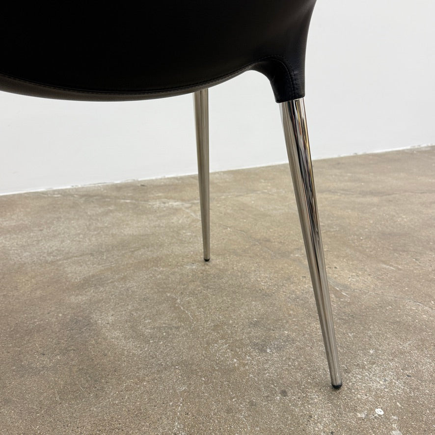 The Cassina Passion Side Chair by Cassina is a modern black upholstered chair with a curved backrest, button detailing, and four sleek metal legs inspired by the Passion design.