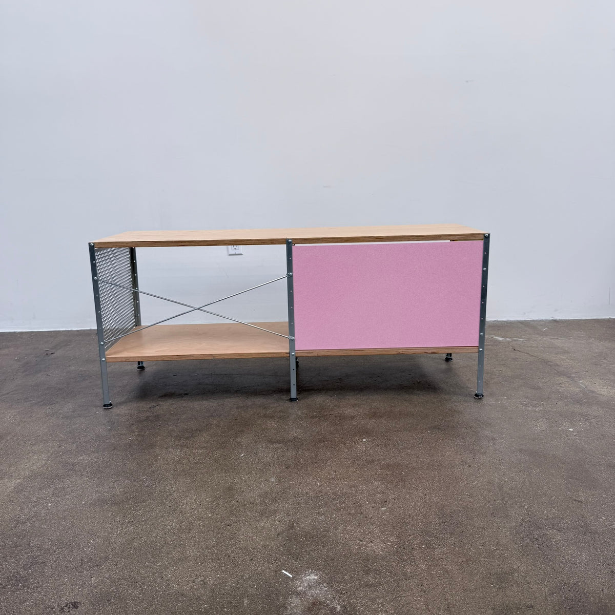 Herman Miller Eames Storage Unit featuring a low rectangular frame with plywood shelves, a yellow side panel, a pink back panel, and a perforated metal side.