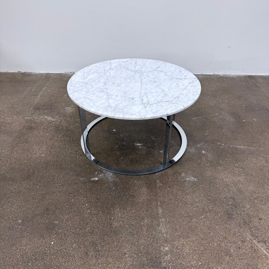 B&B Italia Mera Round Coffee Table with a white Carrara marble top and a dark metal circular base.