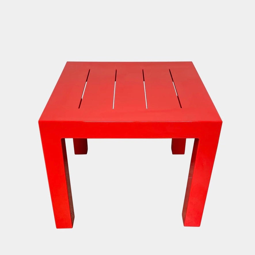 A Vondom Jut Outdoor Table Red, adding a splash of color to an outdoor dining area with its vibrant red shade on a white background.