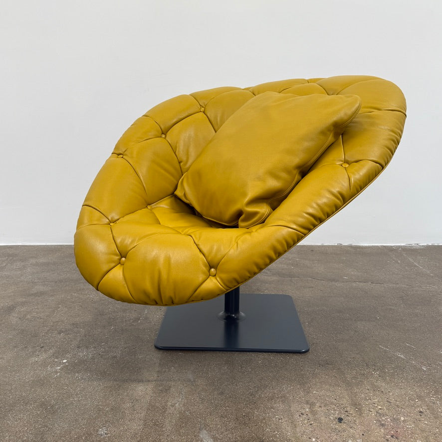 The Moroso Bohemian Low Armchair by Moroso features mustard yellow tufted leather upholstery, a matching cushion, and a black metal pedestal base, shown against a plain white background.