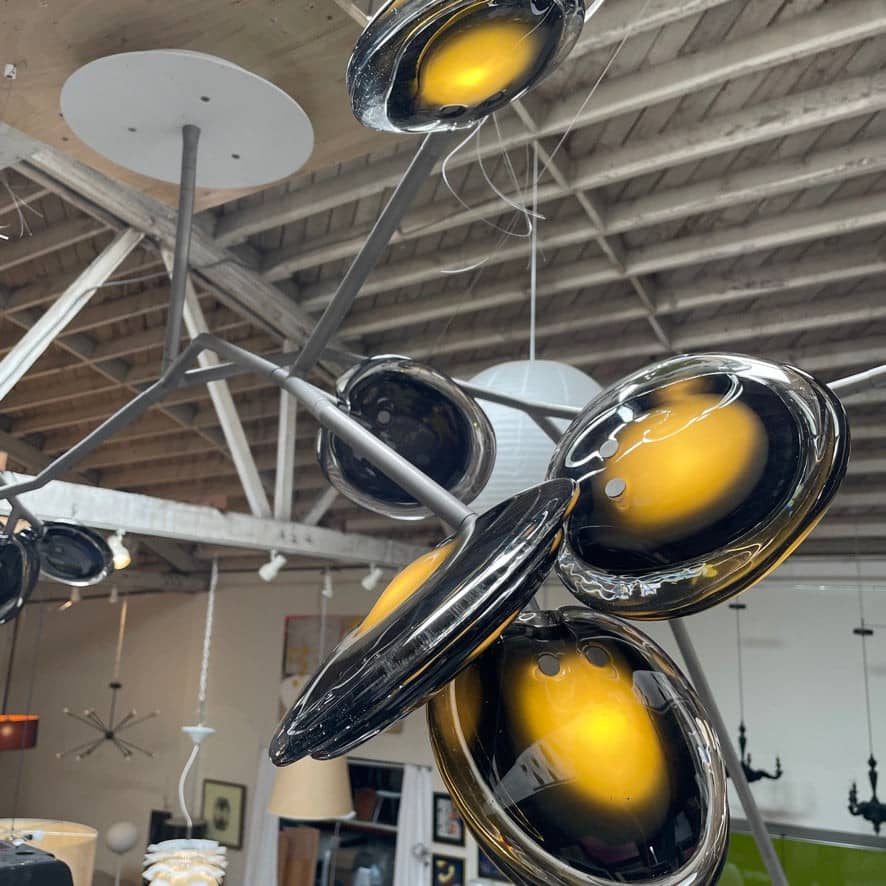 The Bocci Armature Chandelier T16.17aA1 by Bocci features multiple black branches with round, illuminated bulbs extending from a central base, offering a modern ceiling light fixture design inspired by contemporary aesthetics.