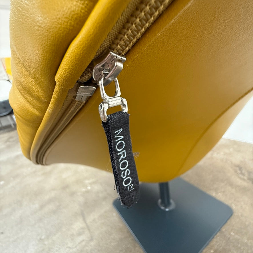 The Moroso Bohemian Low Armchair by Moroso features mustard yellow tufted leather upholstery, a matching cushion, and a black metal pedestal base, shown against a plain white background.