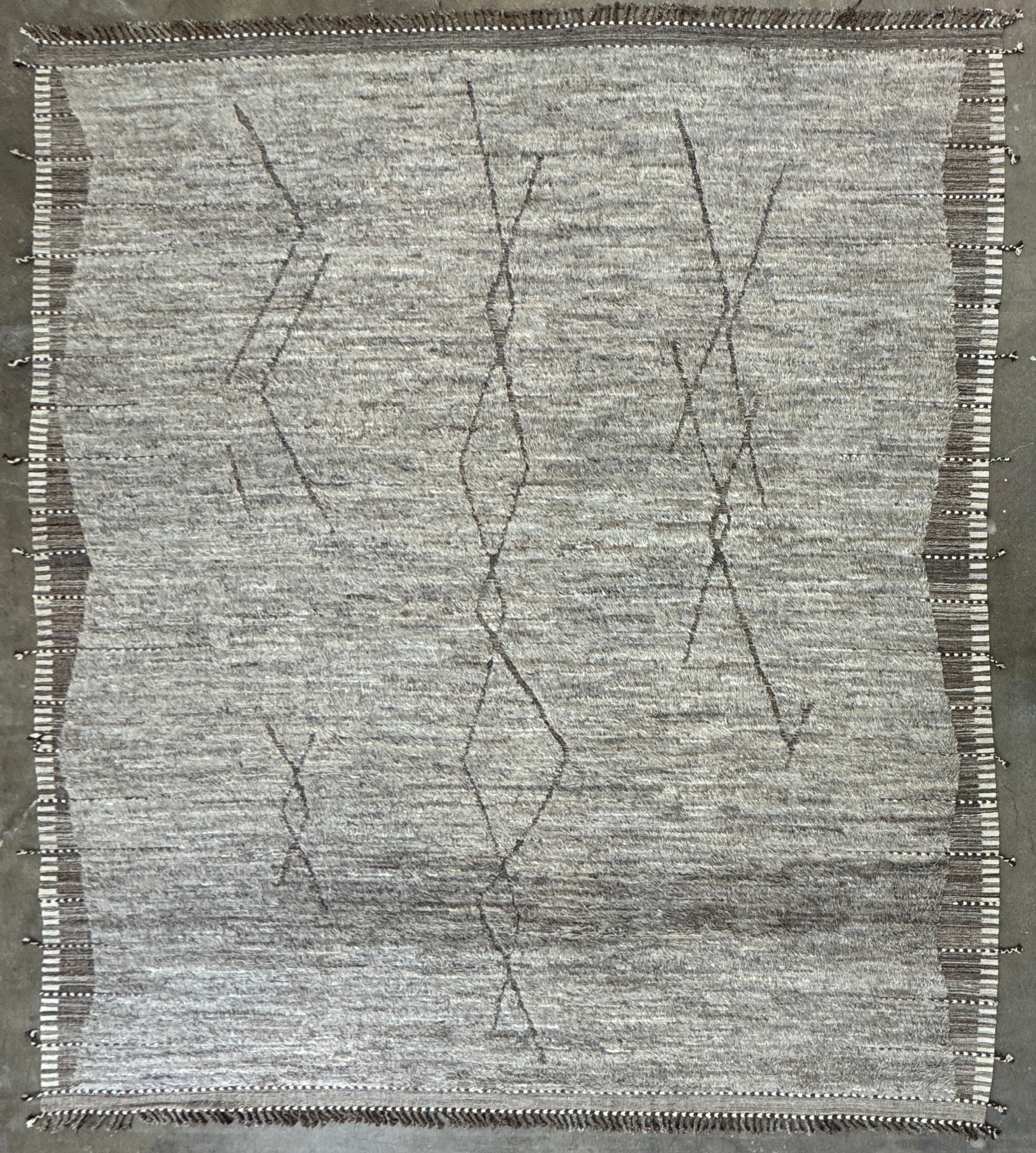 The Mehraban Gilavar Rug (13' x 15'.5") by Mehraban features handwoven, textured neutral tones, fringe tassels on the edges, and striped and patterned designs.